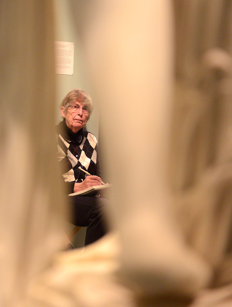 Susan Roberts looks up at a sculpture of three women as she makes a sketch Tuesday
